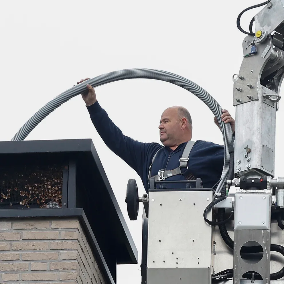 Hendrik-Jan monteert een rookgaskanaal bij een schoorsteen